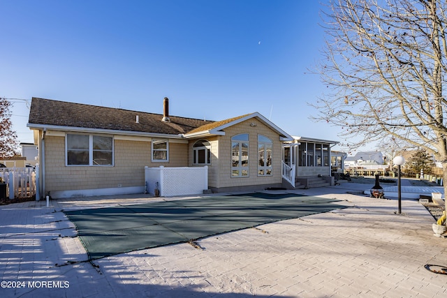 back of property featuring a sunroom, a patio, and a covered pool