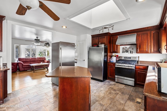 kitchen with ceiling fan, a center island, ventilation hood, appliances with stainless steel finishes, and hardwood / wood-style flooring