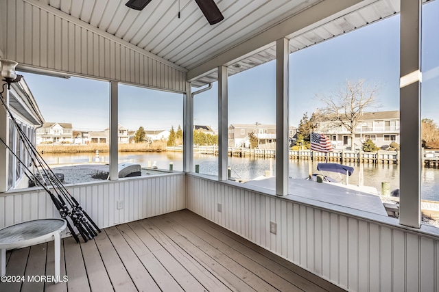 unfurnished sunroom featuring ceiling fan and a water view