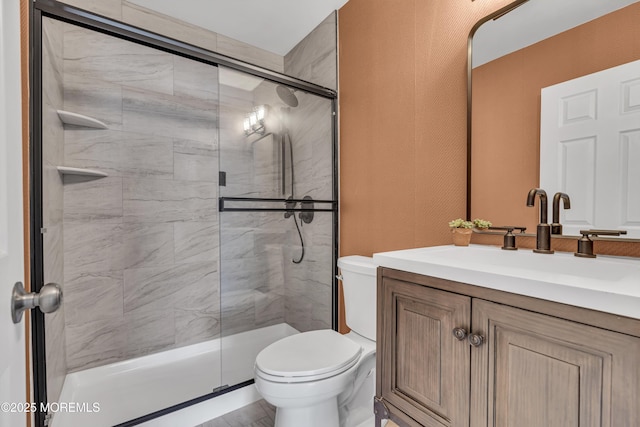 bathroom featuring vanity, toilet, and a shower with shower door