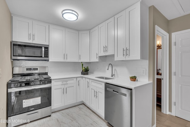 kitchen featuring appliances with stainless steel finishes, tasteful backsplash, white cabinetry, and sink