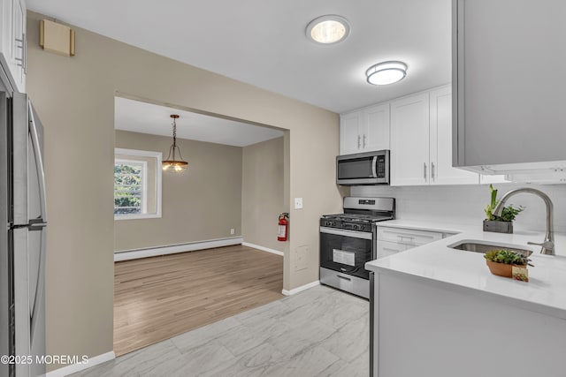 kitchen with tasteful backsplash, stainless steel appliances, baseboard heating, sink, and white cabinets