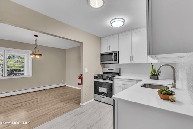 kitchen with white cabinets, stainless steel appliances, a baseboard radiator, and sink