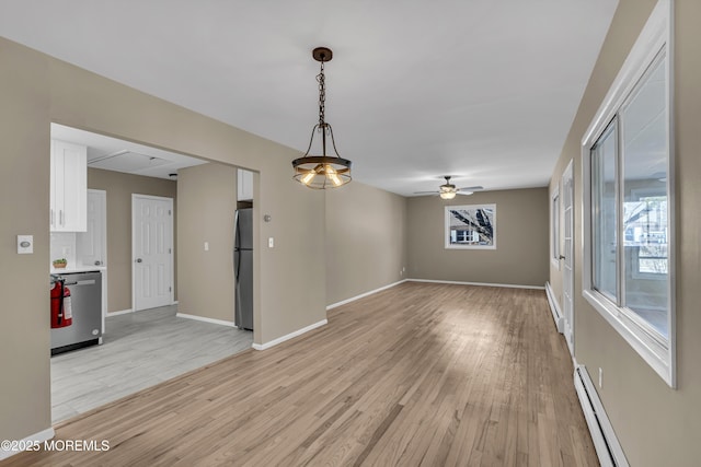 empty room featuring light hardwood / wood-style flooring, ceiling fan, and a baseboard heating unit