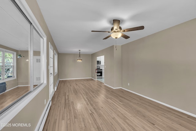 unfurnished room with light hardwood / wood-style flooring, ceiling fan with notable chandelier, and a baseboard heating unit