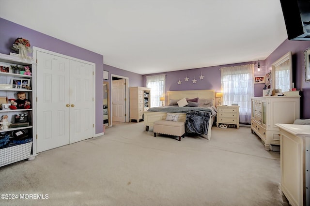 bedroom with multiple windows, light colored carpet, and a closet