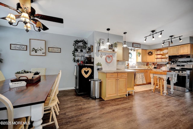 kitchen featuring gas range, dark hardwood / wood-style flooring, decorative light fixtures, and light brown cabinets