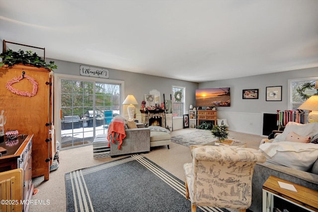 living room with light carpet, a stone fireplace, and a wealth of natural light