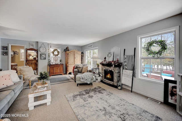 living room with a stone fireplace and carpet floors