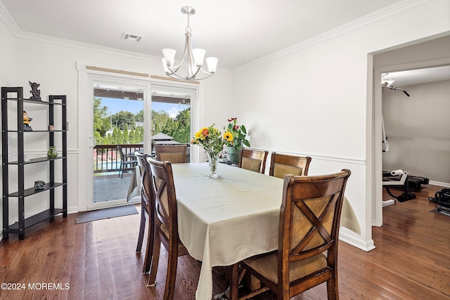 dining room with dark hardwood / wood-style flooring, an inviting chandelier, and ornamental molding