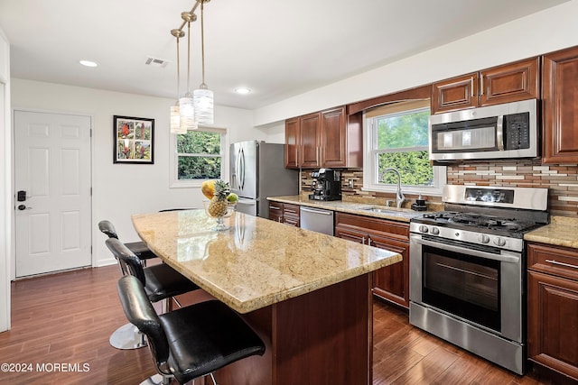 kitchen with sink, tasteful backsplash, a kitchen bar, a kitchen island, and appliances with stainless steel finishes