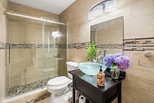 bathroom featuring vanity, toilet, tile walls, and walk in shower