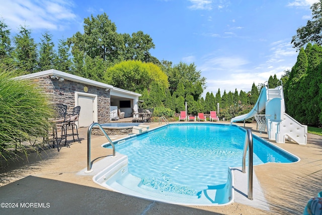 view of swimming pool with a patio area and a water slide