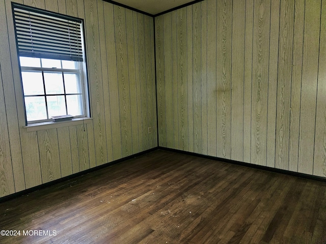 unfurnished room featuring dark wood-type flooring and wood walls