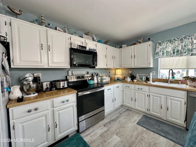 kitchen with sink, white cabinetry, stainless steel appliances, and light hardwood / wood-style flooring