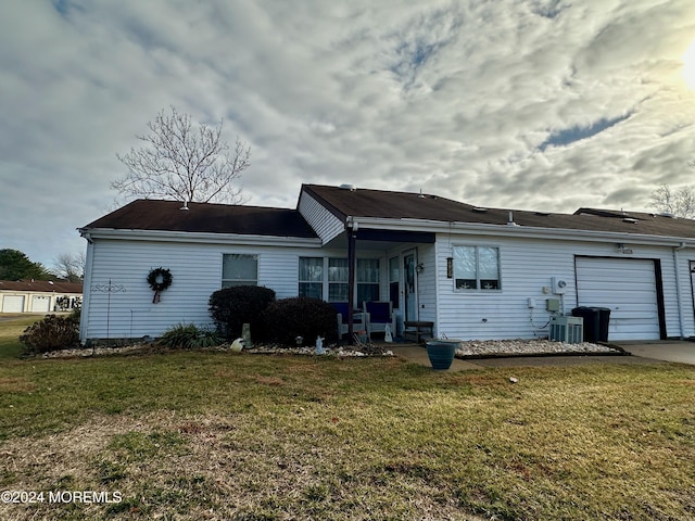 rear view of property featuring a garage and a yard