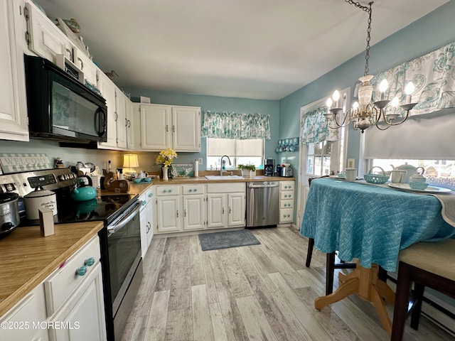 kitchen featuring decorative light fixtures, white cabinetry, sink, stainless steel appliances, and light wood-type flooring