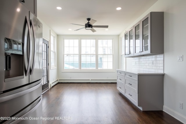 kitchen featuring ceiling fan, stainless steel fridge with ice dispenser, dark hardwood / wood-style flooring, a baseboard heating unit, and backsplash