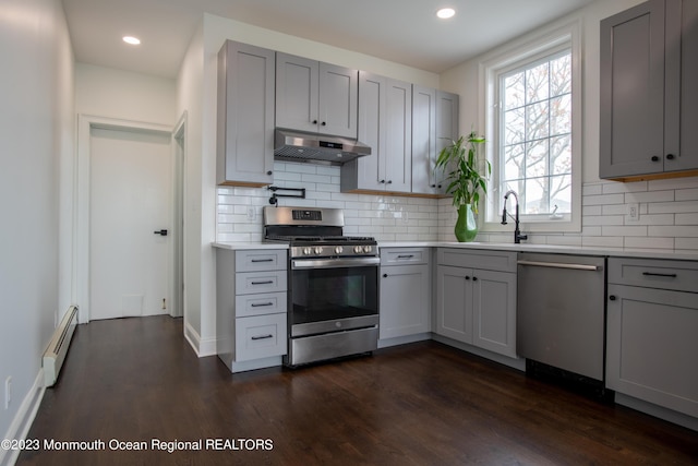 kitchen with gray cabinetry, dark hardwood / wood-style floors, a baseboard heating unit, and appliances with stainless steel finishes