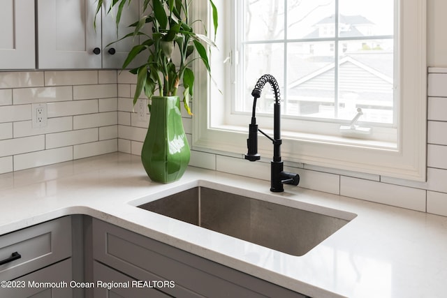 room details with gray cabinetry, backsplash, and sink