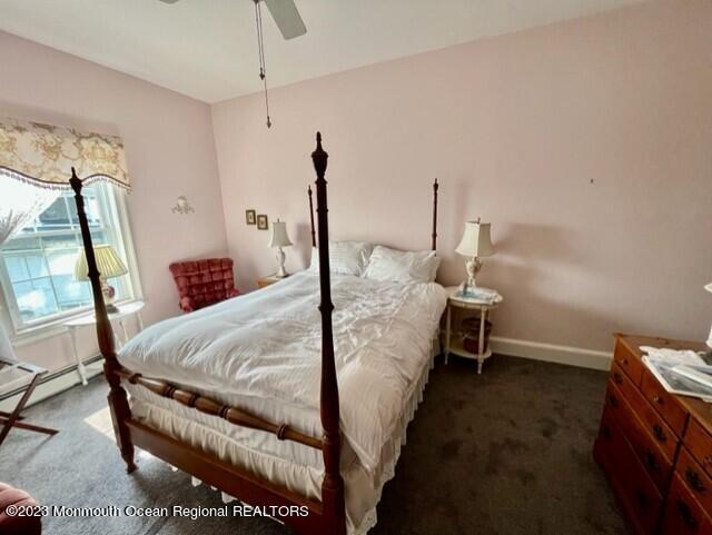 bedroom with dark colored carpet, baseboard heating, and ceiling fan