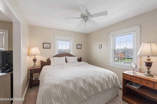 bedroom with ceiling fan, light colored carpet, and a baseboard heating unit