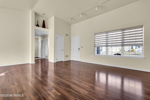 unfurnished living room with high vaulted ceiling, dark hardwood / wood-style flooring, and track lighting