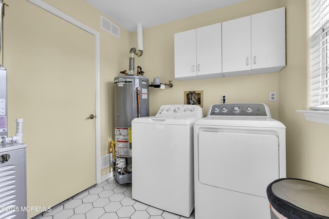 laundry room with cabinets, washer and dryer, and gas water heater