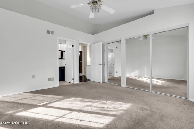 unfurnished bedroom with ceiling fan, multiple closets, carpet floors, ensuite bath, and high vaulted ceiling