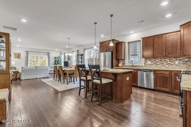 kitchen featuring light stone countertops, decorative light fixtures, stainless steel appliances, and dark hardwood / wood-style floors