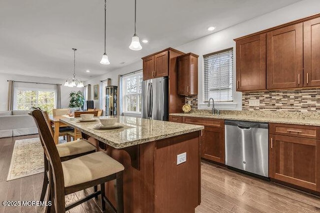 kitchen featuring decorative backsplash, stainless steel appliances, sink, pendant lighting, and a kitchen island