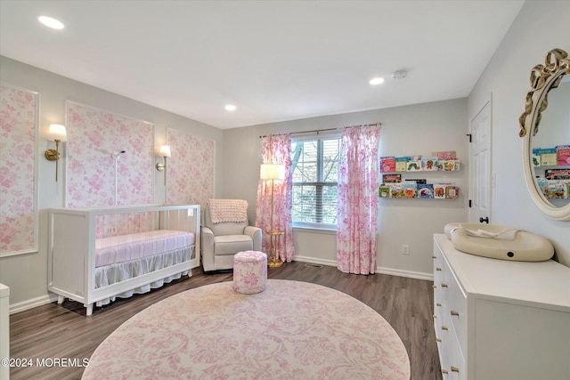 bedroom featuring dark wood-type flooring and a nursery area