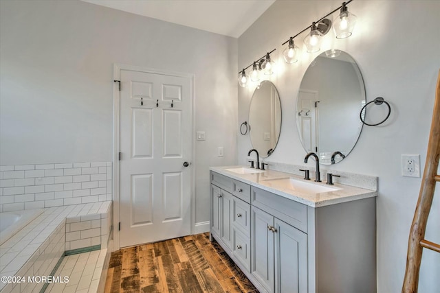 bathroom with vanity, hardwood / wood-style floors, and a relaxing tiled tub