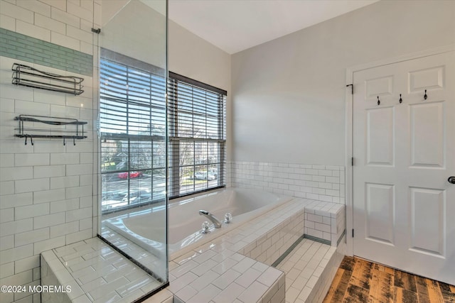 bathroom featuring hardwood / wood-style flooring and tiled tub