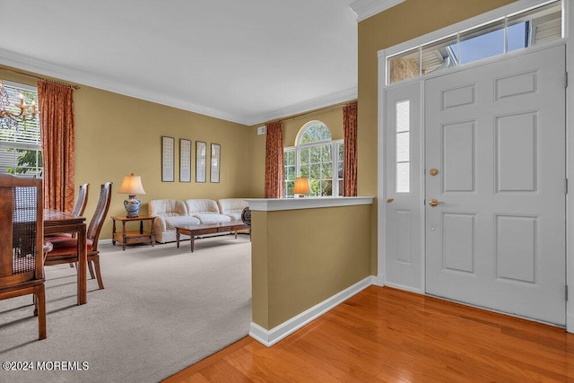 entrance foyer with plenty of natural light, light colored carpet, and ornamental molding