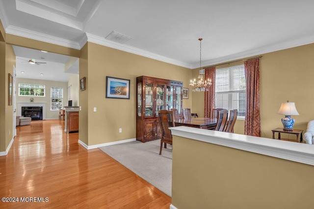 dining room with light wood-type flooring, ceiling fan with notable chandelier, and ornamental molding