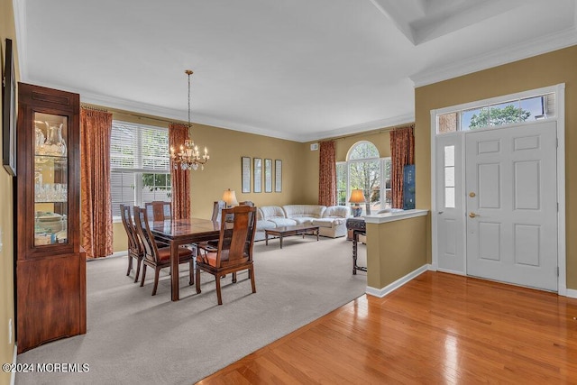 dining space featuring light carpet, plenty of natural light, an inviting chandelier, and ornamental molding