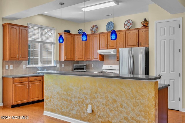 kitchen featuring tasteful backsplash, a kitchen island, range, light hardwood / wood-style floors, and stainless steel refrigerator