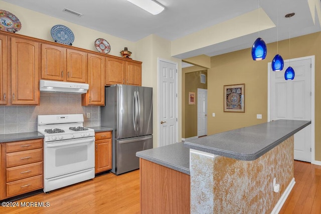 kitchen featuring backsplash, pendant lighting, light hardwood / wood-style flooring, stainless steel refrigerator, and white gas stove