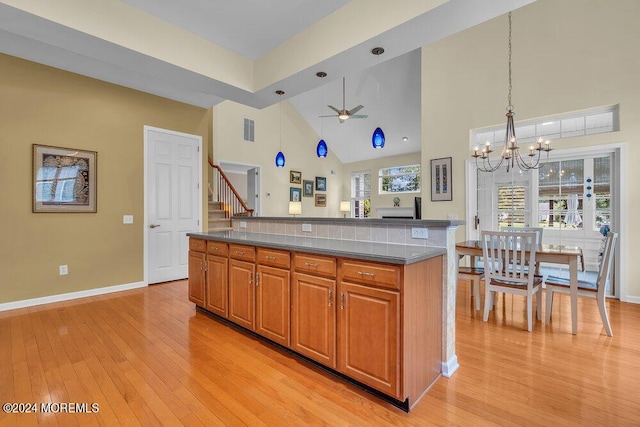 kitchen with pendant lighting, a high ceiling, ceiling fan with notable chandelier, a wealth of natural light, and a kitchen island