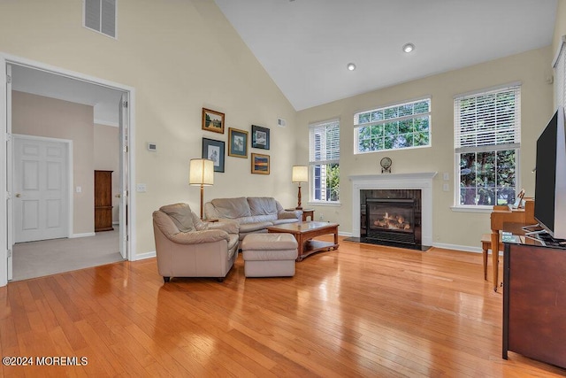 living room with a healthy amount of sunlight, high vaulted ceiling, and light hardwood / wood-style floors