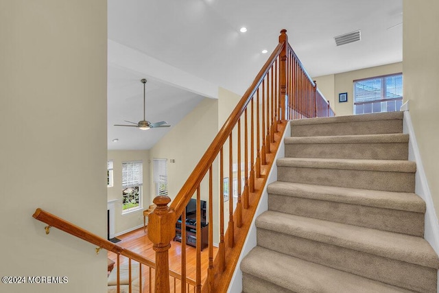 stairs featuring ceiling fan and hardwood / wood-style floors