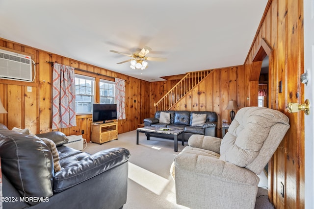 carpeted living room with ceiling fan, wood walls, and a wall mounted AC