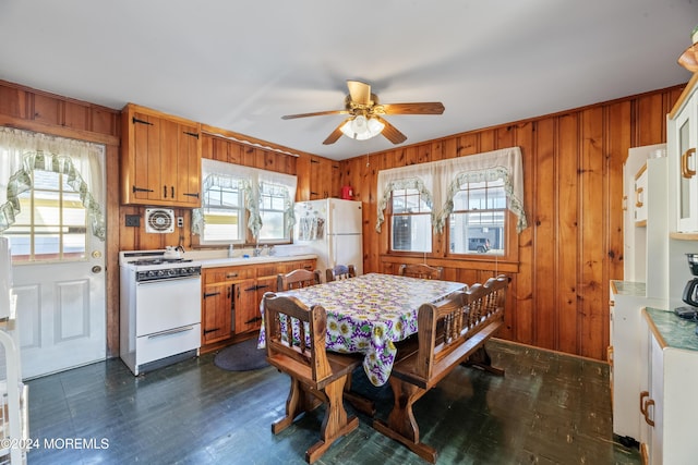 kitchen featuring white appliances, ceiling fan, and wooden walls