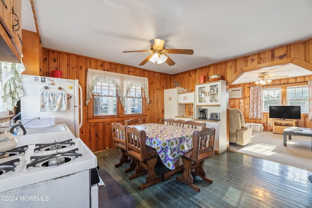 dining room featuring a wall mounted air conditioner, ceiling fan, wood walls, and sink