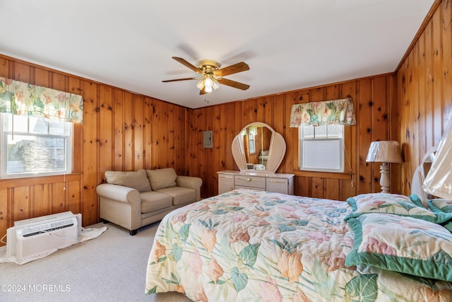 bedroom featuring light colored carpet, a wall unit AC, ceiling fan, and wooden walls