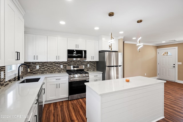 kitchen with appliances with stainless steel finishes, sink, decorative light fixtures, white cabinets, and a center island