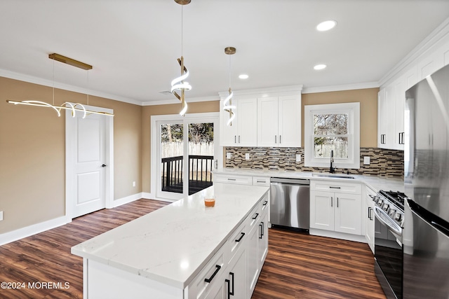 kitchen with white cabinets, a kitchen island, stainless steel appliances, and hanging light fixtures