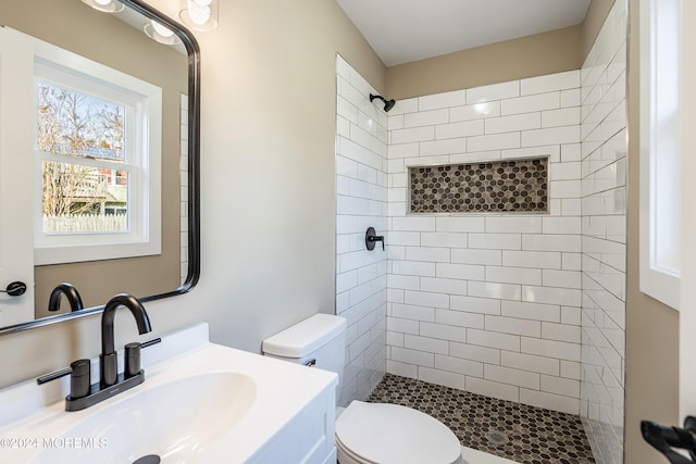 bathroom featuring tiled shower, vanity, and toilet