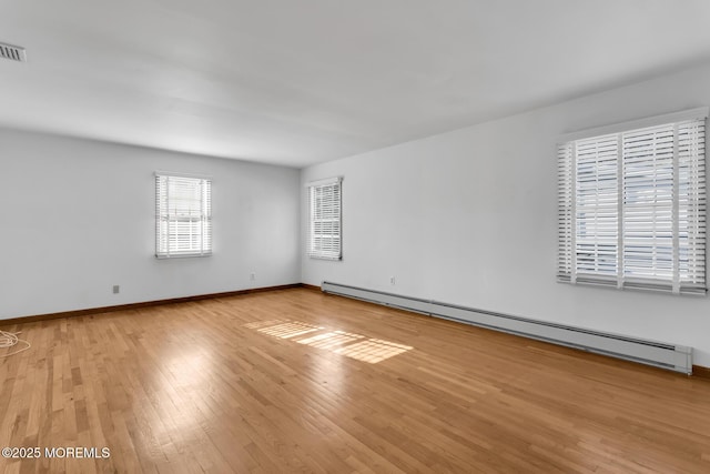 unfurnished room with light wood-type flooring and a baseboard heating unit